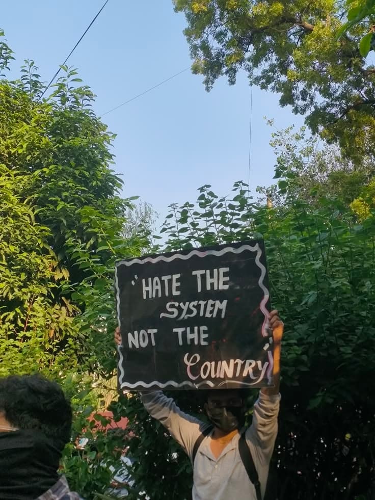 A protester holds a sign reading: Hate the system, not the country